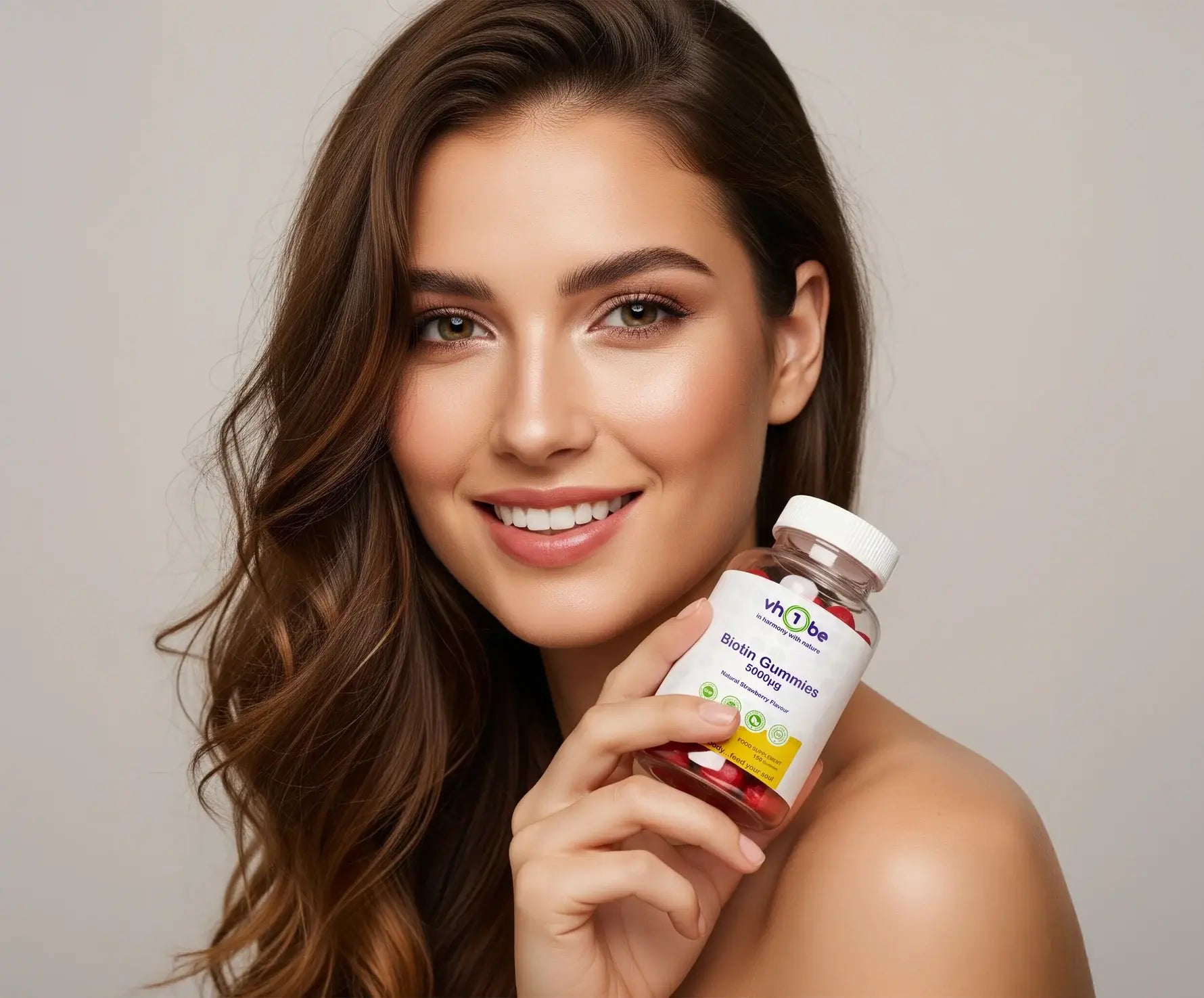 Woman holding a bottle of vitamins against a neutral background